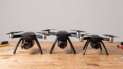 Three camera drones of increasing size lined up on a workbench