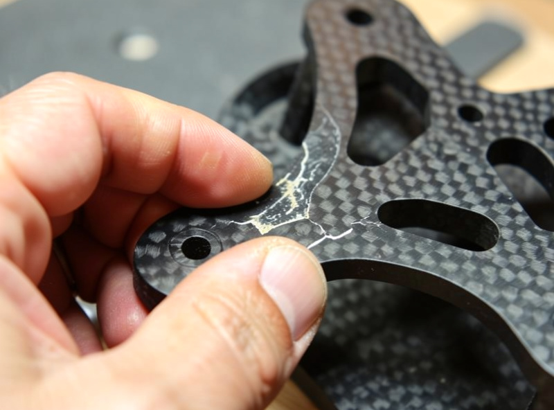 Tap-testing an FPV carbon frame plate for delamination on a workbench