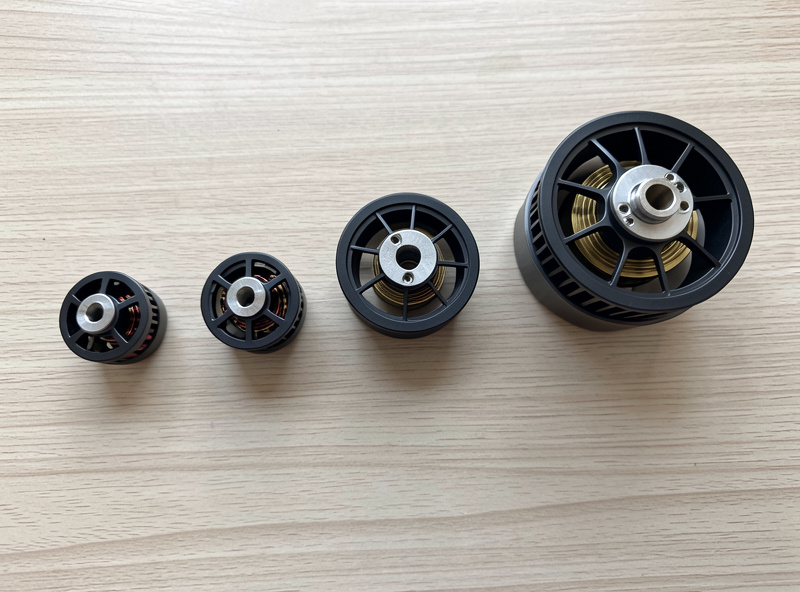 Several FPV motors of different stator sizes lined up on a bench from small to large